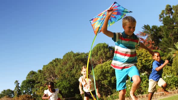 Group of kids running in the park with kite