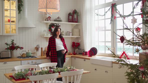 a Pregnant Woman Stands in a Large Bright Kitchen Which is Decorated for Christmas