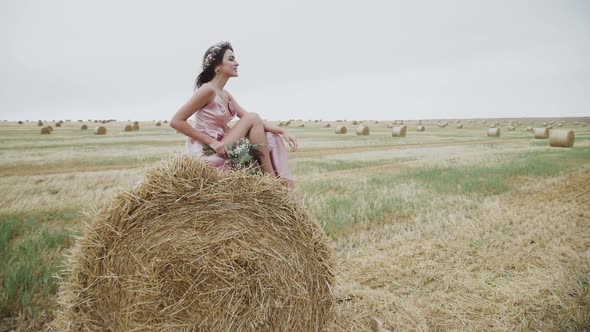 Beautiful Lady in Elegant Dress and Accessories Poses with Joy on Haystack