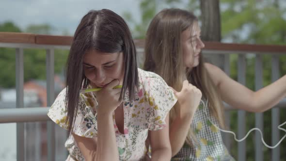 Two Pretty Female Students Sitting Outdoors Together