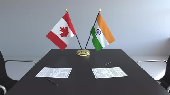 Flags of Canada and India and Papers on the Table