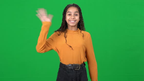 Cheerful Teen African American Girl Waving Looking at Camera Posing at Green Screen