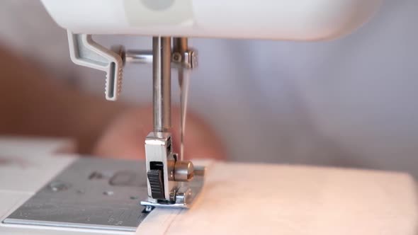 A Woman is Sewing the Hem of Curtains the Edge of a Pillowcase Clothes Sheets on Sewing Machine