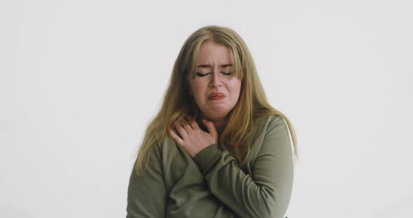 Unhappy Woman Cries Hugging Herself on White Background