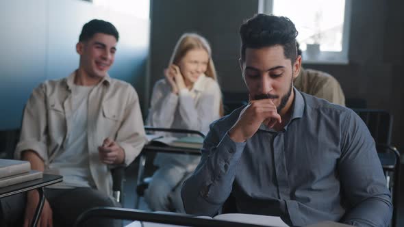 Sad Frustrated Arab Student Sitting in Class at Desk Alone Suffering From Mistreatment By Classmates