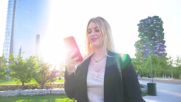 Slow motion shot of businesswoman using red smartphone in park