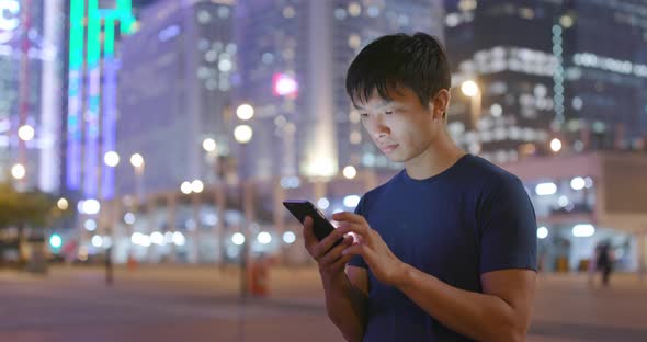 Asian man use of mobile phone in city in the evening