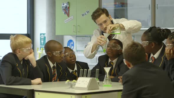 MS Teacher pouring chemical into test tube with his student in laboratory