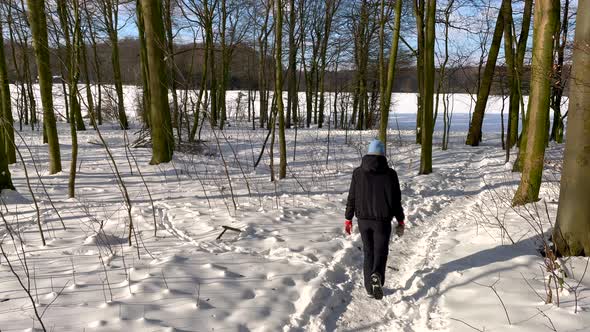 Rear View Of Girl Walking On Snowy Forest During Winter - panning shot