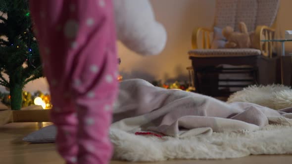 Girl with Teddy Bear Walking to Sleeping Boy on Christmas Evening As Playful Brother Waking Up