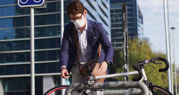 Asian man wearing face mask locking his bicycle at corporate park