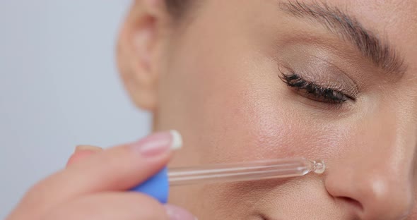 Closeup Beautiful Girl Using Face Oil with Pipette on Her Face