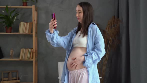 Pregnant Caucasian Woman Having a Video Conference with a Doctor on a Mobile Phone Standing in the