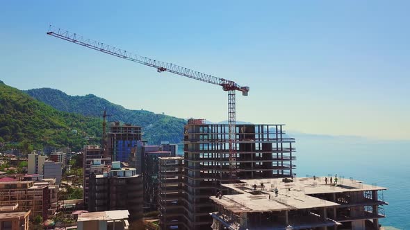 Drone view of construction site multi-storey buildings against background of sea