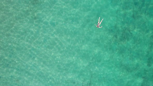 Top Down Aerial View of Woman Swims on Crystal Clear Water in a Transparent Sea