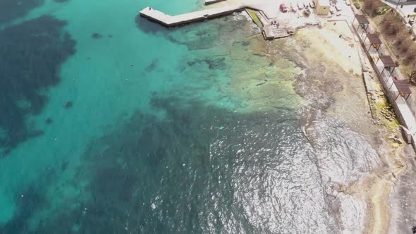 Bird's eye view of Pier extending over Clear Mediterranean water on the shores of Sliema, in Malta