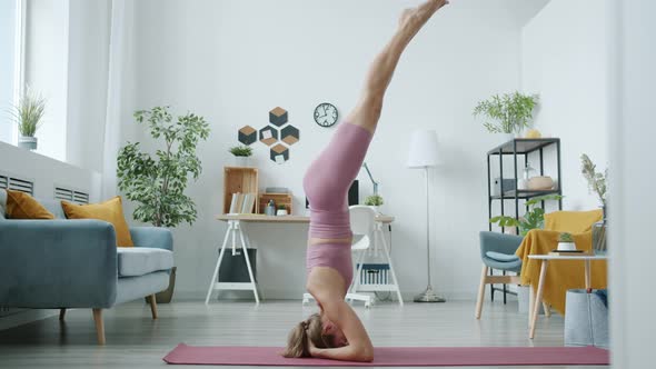 Portrait of Attractive Girl Doing Headstand Enjoying Yoga Exercises Indoors at Home