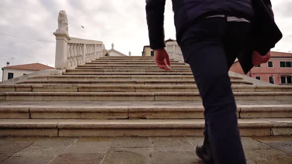 Guy with Modern Laptop Goes Up Marble Steps of Old Bridge