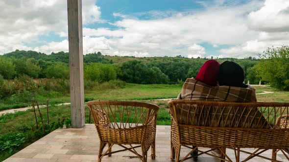 Family Couple Rests in Village House Sitting on Bench and Hugging in Timelapse