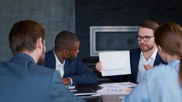 Young leader explaining to colleagues the profit analysis of the company