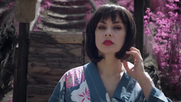 Steadicam Shot of Beautiful Caucasian Woman Dressed Like Japanese Geisha Standing Outdoors on Sakura