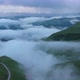 Drone Flight above green fields at the mountains in the clouds and fog. - VideoHive Item for Sale
