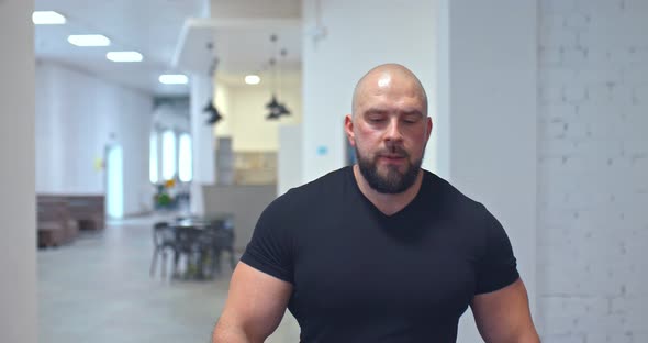 Brutal Man Enters the Gym, the Beginning of Training. Portrait View.