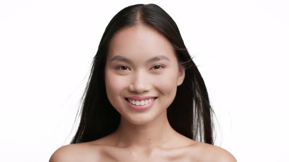 Cheerful Asian Female With Flying Long Brunette Hair White Background