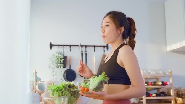 Asian attractive sport woman holding salad bowl and eat vegetables.