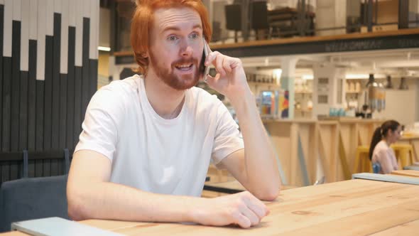 Redhead Beard Man Talking on Phone while Sitting in Cafe