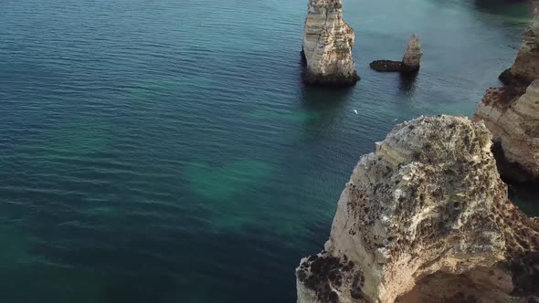 Majestic aerial footage of rocky Algarve coastline in Portugal, overlooking sea cliffs as seagulls f