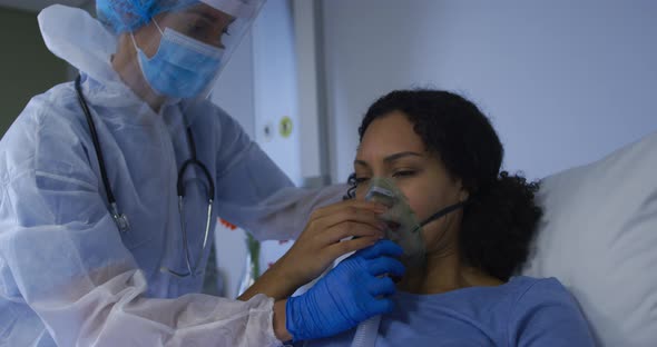 Caucasian female doctor putting on oxygen mask ventilator on african american female in hospital
