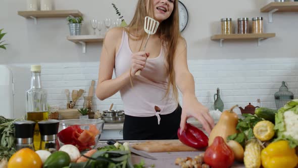 Lovely Vegan Girl with Long Hair Dancing and Singing in Modern Kitchen. Raw Vegetable Food Diet