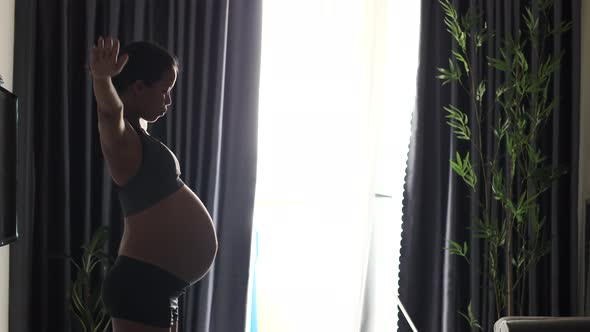 Young Pregnant Woman in Sports Attire Doing Warm Up and Breathing Exercise