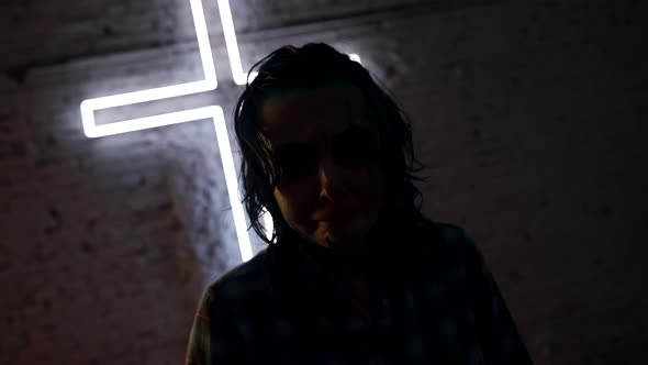 Portrait of a Creature with Strange Makeup at a Glowing Cross