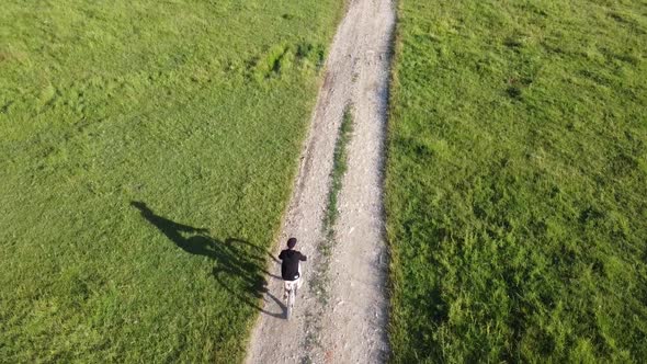 Aerial footage of a male ridding his bike on a country road on a sunny summer day