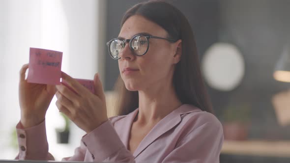 Female Office Worker Attaching Sticky Notes to Glass Wall