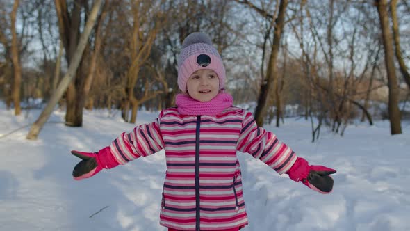 Child Girl Walking on Snowy Road Fooling Around Smiling Looking at Camera in Winter Park Forest