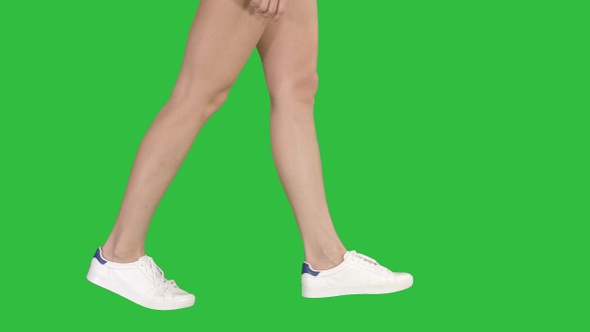 Women feet wearing white sneaker shoes walking on a Green