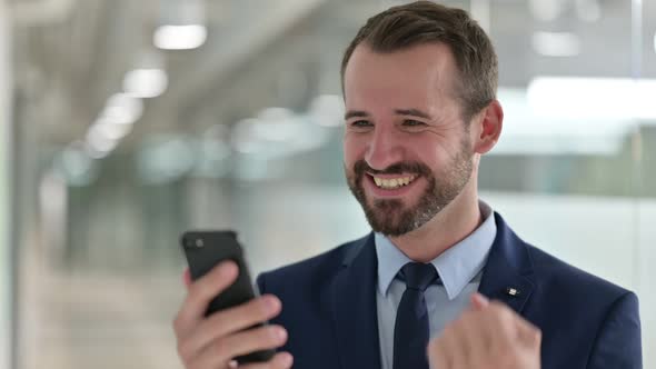 Portrait of Businessman Celebrating Success on Smartphone 