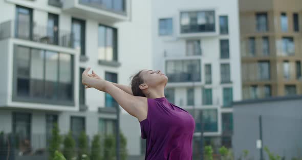 Young Woman Does Stretching Exercises for Hands and Shoulders, Warm-up Training in the Yard of an