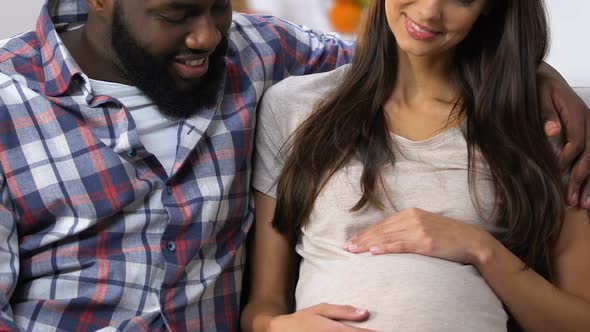 Happy Mixed-Race Couple Waiting for Baby and Smiling Family Planning Clinic