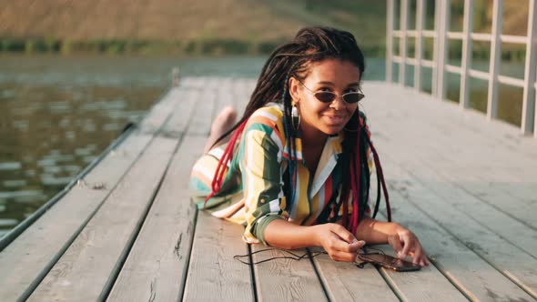 Beautiful AfricanAmerican Girl in Sunglasses Looks at the Phone Chats in Messengers Answers Messages