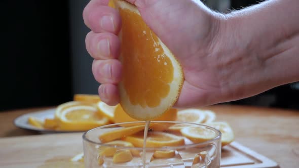 Hand Squeeze Juice From an Orange Into a Glass. Close Up. Slow Motion