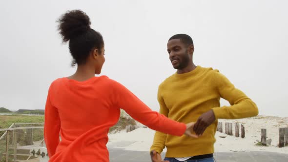 Young romantic black couple dancing together on promenade at beach on a sunny day 4k