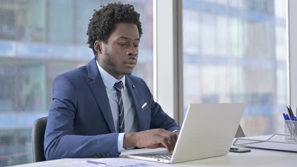 African American Businessman Thinking and Using Laptop in Office