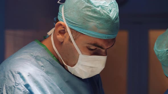 Doctor's Face in a Medical Uniform and a Mask Makes an Operation in the Operating Room