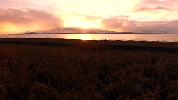 Flying over marsh towards lake during colorful sunset