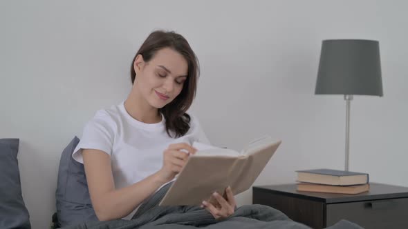 Woman Reading Book While Sitting in Bed