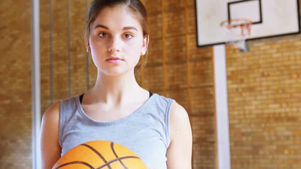 Teenage girl holding a basket ball in the court 4k